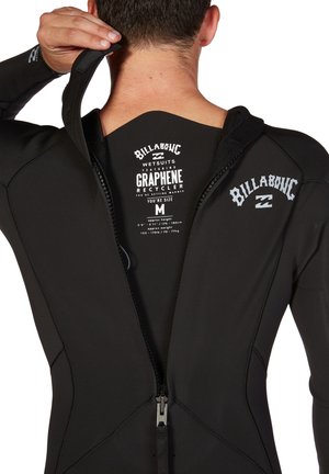 Black wetsuit featuring a rear zipper, smooth texture, and logo detailing. Inside label includes size and care instructions.