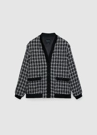 Cardigan en tweed noir et blanc avec col en V, boutons sur le devant, deux poches à rabat, et détails en côtes aux poignets et à l'ourlet.