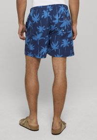 Granatowe spodenki kąpielowe z niebieskim wzorem palm, elastycznym pasem i bocznymi kieszeniami. Miękki materiał o gładkiej fakturze i luźnym kroju.