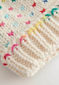 Knit cream-colored hat with multi-colored heart patterns. Features a ribbed edge and textured yarn for warmth and comfort.