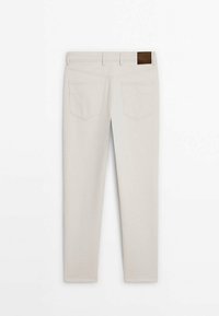 Beiget väri-farkut suoralla leikkauksella, joissa on kaksi takataskua ja ruskea nahkainen merkki vyötäröllä. Sileä pinta.