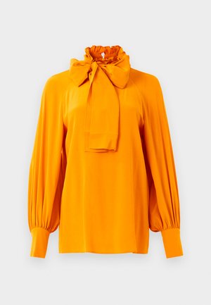 Blouse longue à manches longues orange vif avec un col haut à volants et un grand nœud noué au collier, avec des poignets plissés.