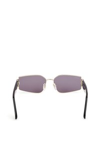 Gafas de sol con un diseño rectangular y anguloso. Presentan lentes grises, montura de metal dorado y varillas de plástico negro con almohadillas nasales transparentes.
