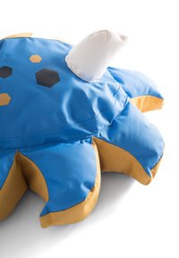 Blå krabbeformet pude med gule accenter, lavet af blødt stof. Har sekskantede og cirkulære mønstre samt en hvid stofaccent på toppen.