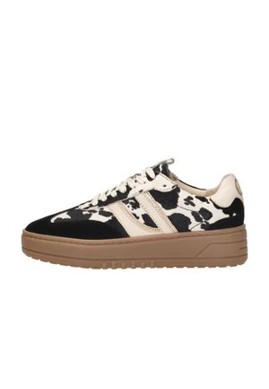 Zwart-witte koeienprint sneaker met een beige suède streep, ronde neus en bruine rubberen zool. Voorzien van witte veter en een gestructureerde afwerking.
