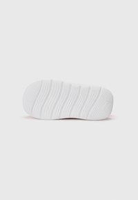 Suela de zapatilla blanca con estrías texturizadas y punta redondeada. Material suave y gomoso con un discreto detalle del logo en el talón.