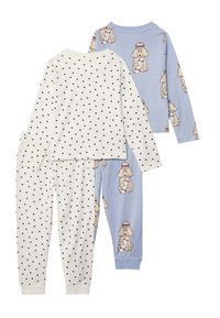 Dos conjuntos de pijamas de manga larga para niños, uno blanco con lunares negros y el otro azul claro con perros de caricatura sosteniendo patinetas.
