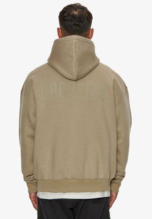 Beige kapucnis pulóver nagy kapucnival és bordás mandzsettákkal. A hátsó részen "DROPSIZE" felirat van debütálva. Puha anyag, laza, oversized fazon.