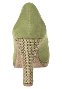 Chaussure à talons hauts en daim vert avec une texture tissée à la base et un talon effilé. Présente des coutures le long de l'arrière, créant une silhouette épurée.