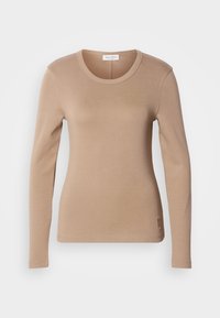 Μακρυμάνικο μπλουζάκι σε ανοιχτό μπεζ, με στρογγυλή λαιμόκοψη και στενή εφαρμογή. Κατασκευασμένο από μαλακό, ελαστικό ύφασμα με λεπτή υφή. Μικρή λεπτομέρεια λογότυπου στο τελείωμα.