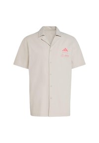 Koszula z krótkim rękawem w jasnobeżowym kolorze. Posiada różowe logo Adidas i Mercedes na lewej piersi. Standardowy krój kołnierzyka.