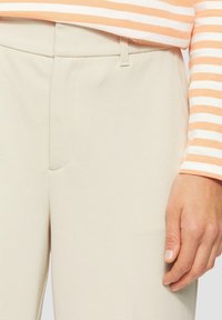Lichtbeige broek van een textiel met structuur, met een platte voorkant, zijzak en een schone, aansluitende pasvorm. Gecombineerd met een gestreept bovenstuk.