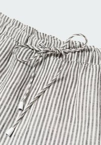 Raidallista kangasta, jossa on ohuet mustat ja valkoiset viivat, elastisella vyötäröllä ja edessä säädettävä nyöri. Rakeinen pinta.