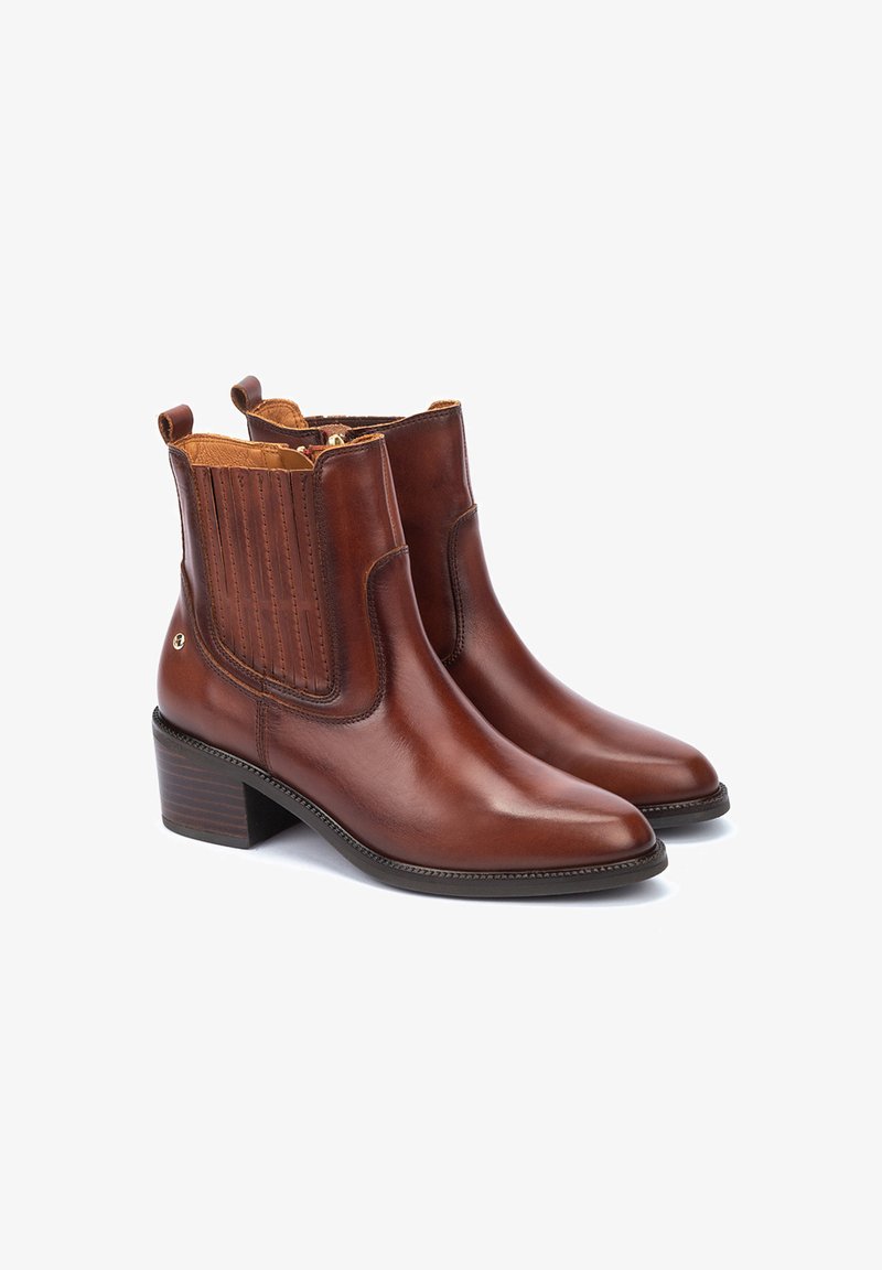 Bottines en cuir marron avec un bout pointu, des panneaux latéraux élastiques et un talon empilé. Présente un design cousu et une fermeture éclair.