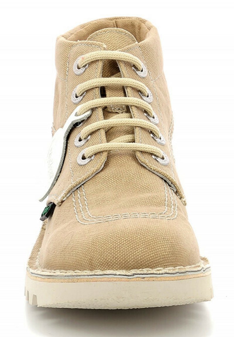 Zapatilla alta de lona beige con costuras blancas, puntera redonda, ojales plateados y cordones planos. Superficie texturizada con una suela de goma ligera.