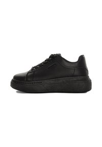 Sneaker in pelle nera con punta arrotondata, lacci piatti e suola spessa. Presenta una texture liscia e un design minimalista.