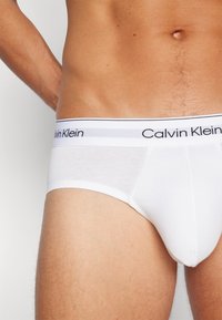 Fehér pamut alsónadrág fekete és szürke Calvin Klein logós derékpánttal, sima textúrával és testhezálló fazonnal.