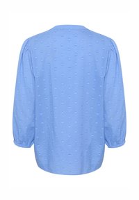 Svetlomodrá blúzka s jemným vzorom srdiečok, zošitými dlhými rukávmi a zaobleným výstrihom. Vyrobená z mäkkej, textúrovanej látky.