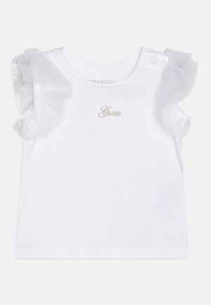 T-shirt branca de algodão com mangas de ruffles transparentes e um pequeno logótipo "Guess" bordado em dourado na frente. Apresenta fecho de pressão no ombro.