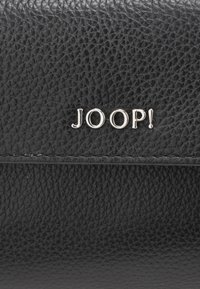 Svart teksturert skinnlommebok med sølvfarget "JOOP!"-logo. Har en glatt overflate og synlige sømmer langs kantene.