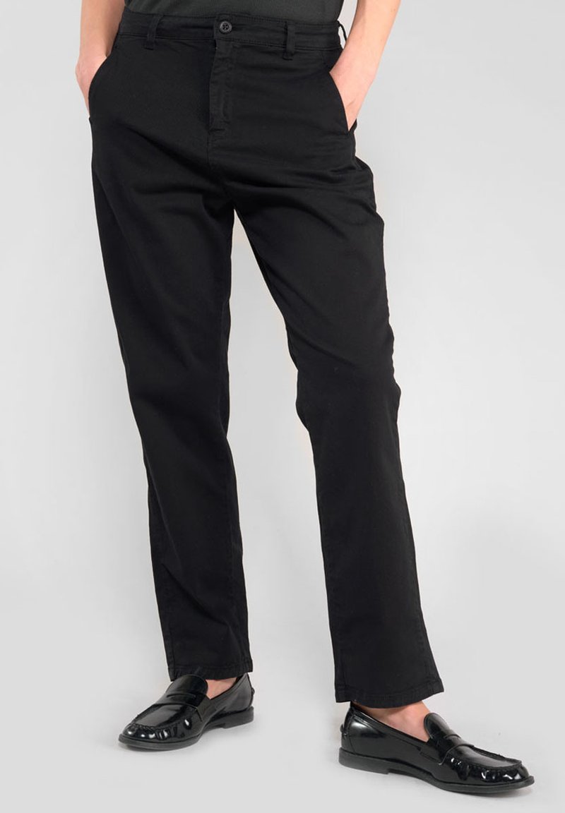 Zwarte chino's van glad katoen met een rechte snit, voorzien van zijzakken en een knoopsluiting, gecombineerd met glanzende zwarte loafers.