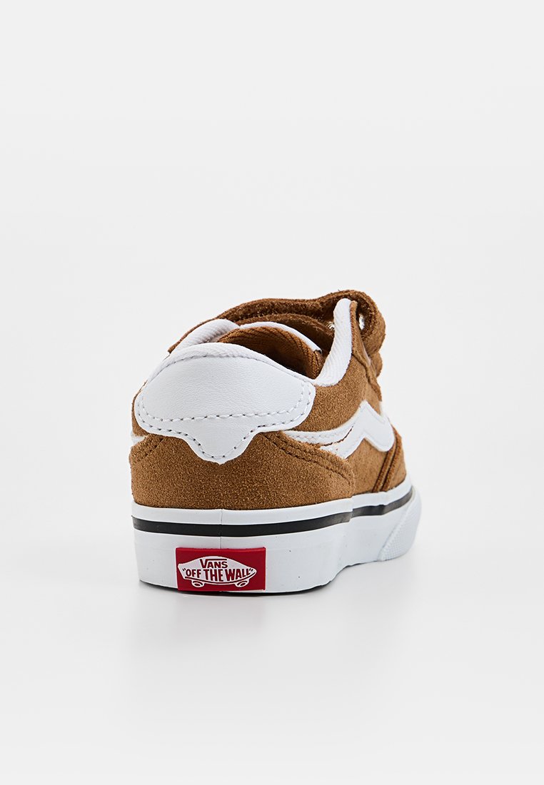 Brązowe zamszowe trampki z białymi akcentami, wyściółką na kołnierzu, płaskimi sznurowadłami i gumową podeszwą. Posiadają charakterystyczne logo Vans w kolorze czerwonym i białym na pięcie.