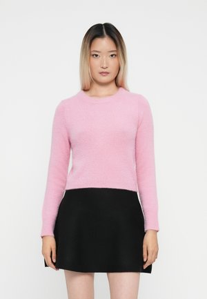 Suéter rosa, de punto suave, con mangas largas y escote redondo, combinado con una falda negra entallada, que presenta una textura de tela suave.