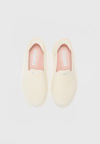 Pantofi albi slip-on cu un design din plasă, având o căptușeală interioară roz și accente texturate pe partea superioară. Culoare neutră și construcție ușoară.