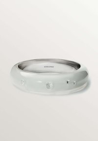 Pulsera de resina transparente con forma suave y redondeada. Presenta tres cristales incrustados y un interior plateado con el nombre de la marca "aristocrazy."