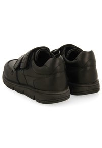 Chaussures en cuir noir avec une texture lisse, forme arrondie et bandes Velcro. Talon renforcé et semelle rembourrée pour le confort.