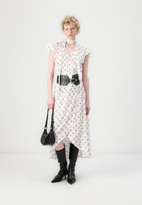 White dress with red cherry print, ruffled sleeves, wrap style, black leather belt, matching handbag, knee-high black boots, angled hem.