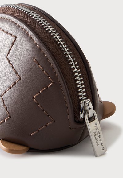 Gros plan d'une pochette en cuir marron avec un motif de couture en zigzag, une fermeture éclair en tissu marron et un curseur de fermeture éclair argenté étiqueté "WEEKEND MaxMara."