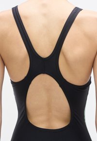 Μαύρο ολόσωμο μαγιό με σχέδιο racerback, ανοιχτή πλάτη και υφασμάτινες ραφές με ανάγλυφη υφή. Ομαλό ύφασμα με διακριτικές λεπτομέρειες.