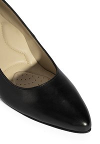 Zwarte leren pump met een spitse neus, een gladde textuur en een gebogen snit aan de bovenkant. Het interieur beschikt over een geperforeerde inlegzool.