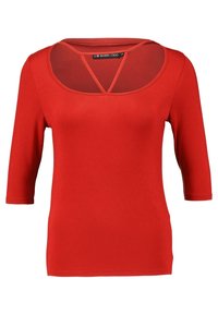 Top de jersey rojo con escote redondeado, panel de malla transparente y mangas tres cuartos. Textura suave y silueta ajustada.