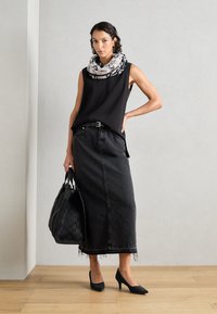 Top senza maniche nero, gonna in denim nero con orlo frangiato, décolleté nere e borsa nera strutturata con manici doppi. Il foulard presenta un motivo bianco.