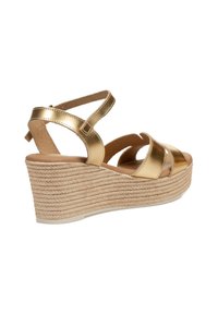 Sandalia cuña dorada con suela de cuerda trenzada y correas ajustables en el tobillo, que presenta un diseño elegante y un estilo de punta abierta.