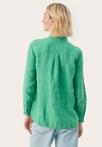 Grøn linnedskjorte med rygpanel, lange ærmer, knapmanchetter og en afslappet pasform. Stoffet har en struktureret overflade.