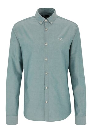 Grünes Hemd mit langen Ärmeln, durchgehender Knopfleiste, geknöpftem Kragen und einer kleinen Stickerei mit gekreuztem Schwert und Feder auf der Brust.