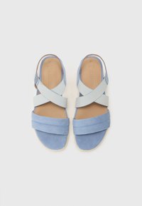 Sandales en suède bleu avec un design à lanières croisées ; dessus texturé, semelle plate et semelle en dessous beige. Les lanières en tissu doux offrent un ajustement sécurisé.