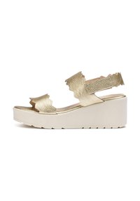 Sandalias de cuña texturizadas en dorado con correas onduladas y suela de plataforma ancha, que presentan un acabado beige suave y diseño sin hebillas.