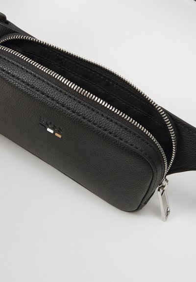 Sac bandoulière en cuir noir avec surface texturée, fermeture éclair argentée et accent logo. Dispose d'un seul compartiment de rangement.