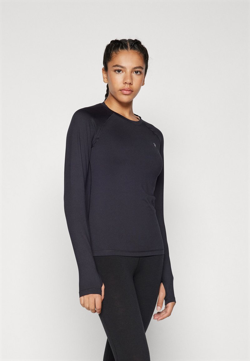 Langermet treningstopp i svart stoff, med rund hals og lette sømdetaljer. Kombinert med svarte leggings for et enhetlig utseende.