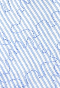 Blauw-witte gestreepte stof met een verhoogd, golvend patroon gestikt in lichtblauw garen, wat een textuuroppervlak creëert.