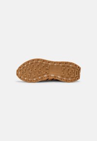 Suola in gomma di sneaker con un motivo di battistrada geometrico, di colore beige con dettagli del marchio in rilievo e informazioni sulla taglia.