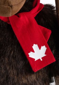 Brown plush moose figure wearing a red scarf with a white maple leaf patch. The scarf is tied around the neck, contrasting with dark fur.
