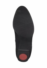 Suela de zapato negra con goma texturizada, que presenta un patrón ondulado y un acento rojo en el talón etiquetado como "Confort". Diseñada para ofrecer agarre y durabilidad.