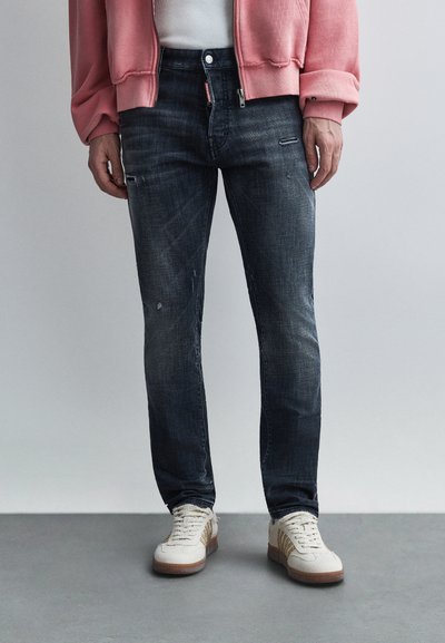 Jean en denim bleu foncé à coupe slim, présentant un léger délavage, des accents usés et un design classique à cinq poches.