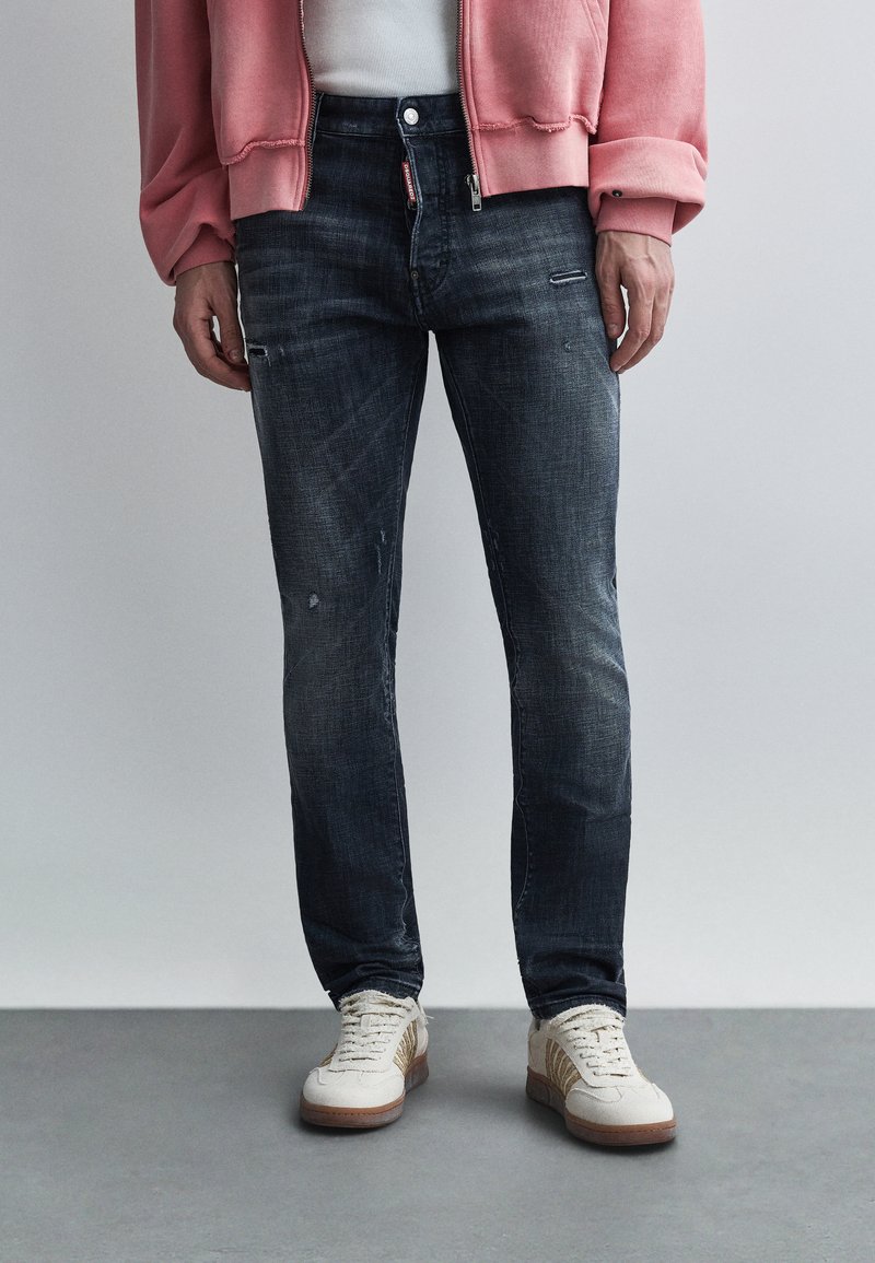 Σκούρο μπλε τζιν με στενή γραμμή, με διακριτική ξ εθώριαση, φθορές και κλασικό σχέδιο με πέντε τσέπες.