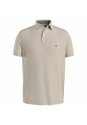 Beżowa koszulka polo z krótkim rękawem, z plisą na dwa guziki i małym logo flagi Tommy Hilfiger po lewej stronie klatki piersiowej.